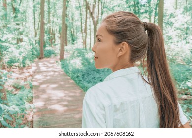 Sustainable eco-friendly lifestyle happy Asian woman hiking on walking path in green forest during summer, young adult looking up at trees. Environment concept.