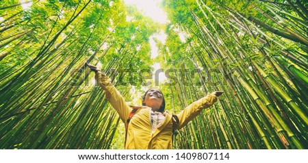 Sustainable eco-friendly travel tourist hiker walking in natural bamboo forest happy with arms up in the air enjoying healthy environment renewable resources.