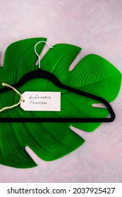 Sustainable Fashion Label With Clothes Hanger On Top Of Tropical Green Leaf On Pink Background Shot At Shallow Depth Of Field, Concept Of Environmentally Conscious Clothing Brands