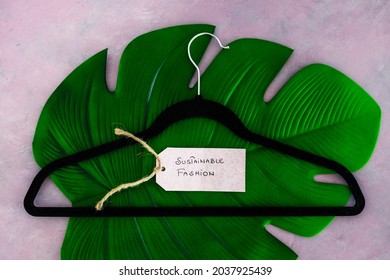 Sustainable Fashion Label With Clothes Hanger On Top Of Tropical Green Leaf On Pink Background Shot At Shallow Depth Of Field, Concept Of Environmentally Conscious Clothing Brands