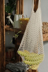 Sustainable Lifestyle, Zero Waste And Plastic Free Concept. Eco Friendly Reusable Shopping Bag. String Bag With Fresh Bananas Hanged On Wooden Rack.