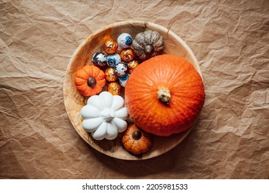 Sustainable and low waste Halloween candy for trick-or-treating. Foil covered eyeballs candies and Halloween decor in wooden plate - Shutterstock ID 2205981533