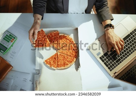 Sustainable workplace. Upper view of small business owner woman in green office with pizza and laptop.