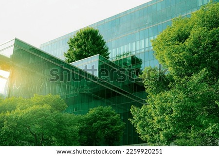 Sustainble green building. Eco-friendly building. Sustainable glass office building with tree for reducing carbon dioxide. Office with green environment. Corporate building reduce CO2. Safety glass.