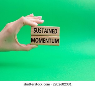 Sustained Momentum Symbol. Wooden Blocks With Words Sustained Momentum. Beautiful Green Background. Businessman Hand. Business And Sustained Momentum Concept. Copy Space.