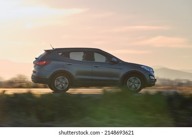 SUV car driving fast on intercity road at sunset. Highway traffic in evening