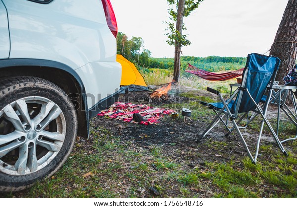 suv car at lake beach camping fire and hammock\
between trees