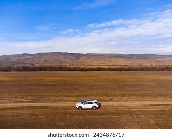 SUV car on a desert landscape. Vast territory. Mountains and rocks in the background.