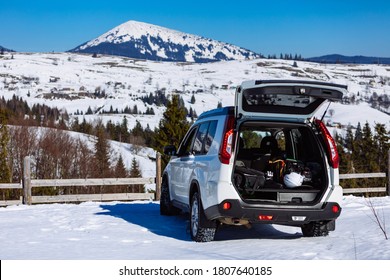suv car parked with opened trunk full of ski and snowboard equipment