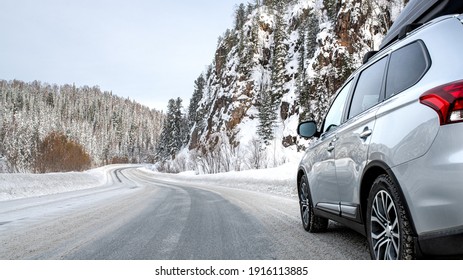 Suv car with rooftop cargo carrier trunk stay on roadside of winter road. Family trip to ski resort. Winter holidays adventure. car on winter road