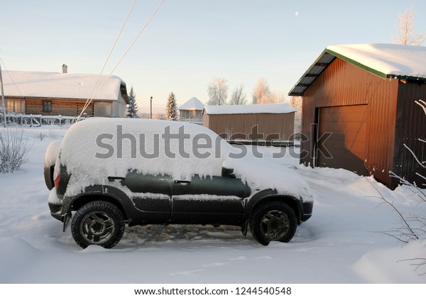 SUV covered with snow is\
in the yard