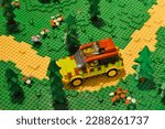 an SUV driving off road on a forest trail  surrounded by trees and flowers, made using LEGO toy blocks