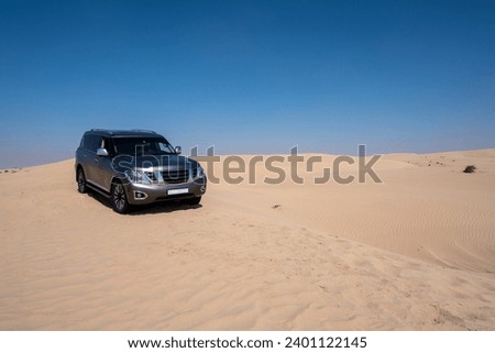 SUV four wheel drive vehicle car Al Qudra empty quarter seamless desert sahara in Dubai UAE middle east with wind paths and sand hills gray cloudy sky