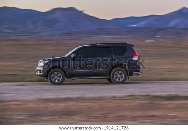 SUV moves along a country road along the fields\
and mountains. Blurry\
motion