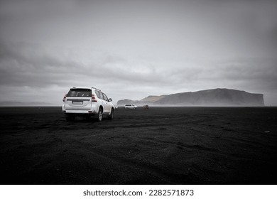 An SUV Is Parked On The Famous Black Sand Beach, With A Mountain In TheBackground in The Distance - Powered by Shutterstock