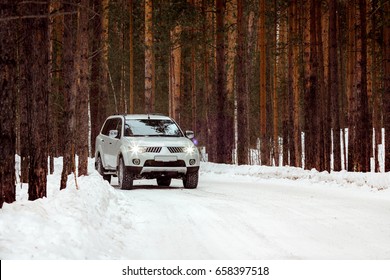 SUV rides on a winter forest road. A car in a snow-covered road among trees