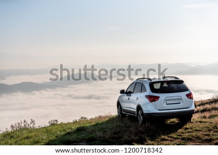 suv vehicle at top of a mountain with clouds on sunset.