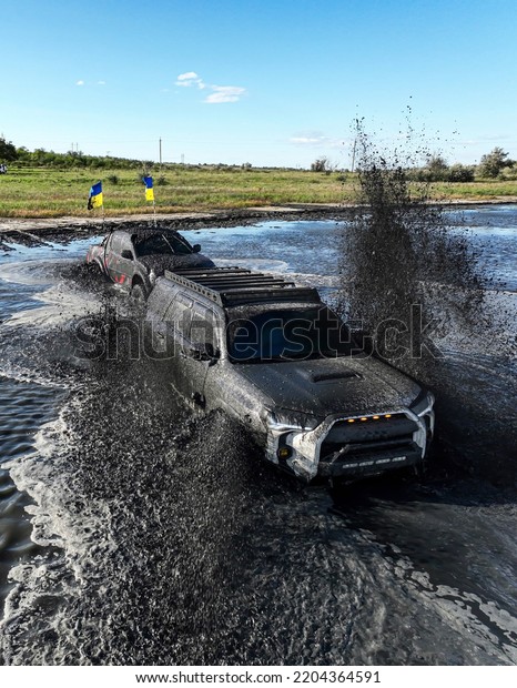 SUVs stuck in the middle of the\
river in the swamp.  Can\'t leave.  Off-road competitions.  Drone\
view.  One truck is trying to get another out of the\
water.