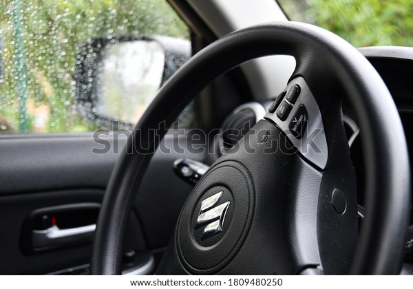 Suzuki\
car driver steering wheel with control panel buttons. Black\
dashboard and wheel of new automobile and blurred background of\
raindrops on windows. Odessa, Ukraine, 09 05\
2020