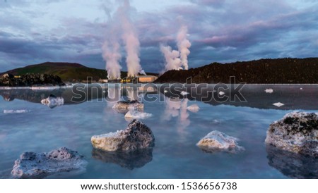 Svartsengi Geothermal Power Plant in Iceland steaming massively with reflection in a blue water of geothermal pool after the sunset and dramatic blue violet sky with thick clouds 