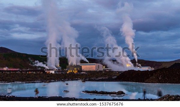 アイスランドのスバルツェンギ地熱発電所で、夕日の後、地熱プールの青い水に反射して大量に蒸し、濃い雲を持つ劇的な青紫色の空