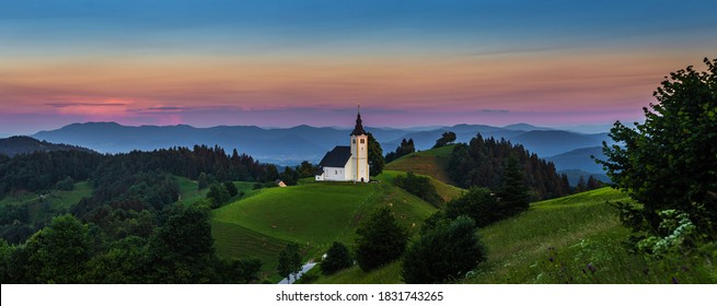 Sveti Andrej, Slovenia - Panoramic view of Saint Andrew church (Sv. Andrej) at sunset in Skofja Loka area with Julian Alps and colorful sky at background. Summer time in the Slovenian alps