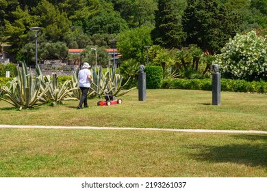 Sveti Stefan, Montenegro - June 6, 2022: A Worker Mows The Grass In A Public Park