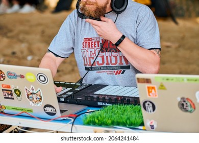 Svetlogorsk, Russia - 08.14.2021 - Disc jockey playing music, remixing on drum machine midi controller. DJ playing beat sampler with drum pads and samples. Deejay makes beats at beach party, close up