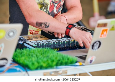 Svetlogorsk, Russia - 08.14.2021 - Disc jockey hands playing music, remixing on drum machine midi controller. DJ playing beat sampler with drum pads and samples. Deejay makes beats at party outside
