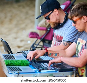 Svetlogorsk, Russia - 08.14.2021 - Disc jockeys playing music, remixing on drum machine midi controller. DJs playing beat sampler with drum pads and samples. Deejays make beats at beach party outdoor