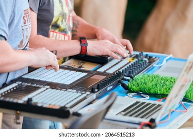 Svetlogorsk, Russia - 08.14.2021 - Disc jockeys playing music, remixing on drum machine midi controller. DJs playing beat sampler with drum pads and samples. Deejays make beats at party, close up