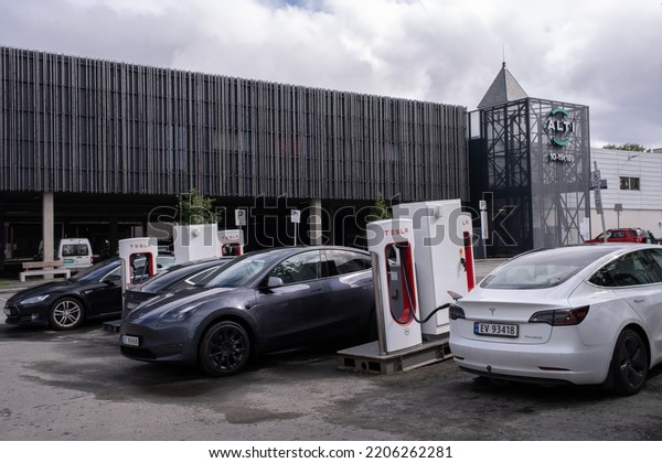 Svolvaer, Norway - July 16,\
2022: A static shot of a solid black Tesla Model 3 dual motor\
charging at the Svolvaer Supercharger in a cloudy summer day.\
Selective focus.