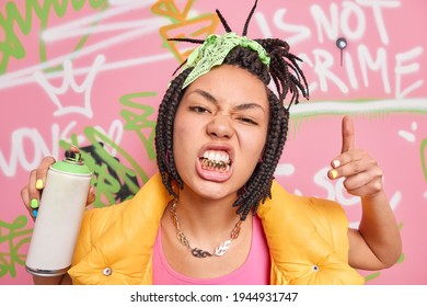 Swag. Fashionable Hipster Girl Rapper With Dreadlocks And Golden Teeth Goes Out To Paint In Public Places Holds Spray Aerosol Creats Graffiti On Walls Being Passionate Street Artist. Young People