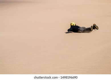 Swakopmund, Namibia, November 2012: Man Sliding Down On A Board, Sandboarding, In The Namibian Dunes