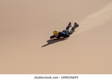 Swakopmund, Namibia, November 2012: Man Sliding Down On A Board, Sandboarding, In The Namibian Dunes