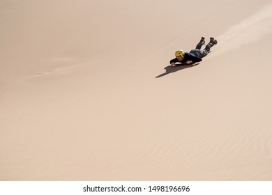 Swakopmund, Namibia, November 2012: Man Sliding Down On A Board, Sandboarding, In The Namibian Dunes