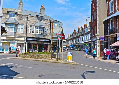 Swanage, Dorset / England - 6/26/2019: General street scene of Swanage town centre at the junction of High Street & Institute Road. People walking along pavements browsing in shops.
