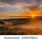 Swansea beach at sunset with Mumbles head and lighthouse in the distance