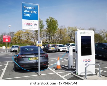 Swansea, UK: April 20, 2021: Pod Point is a leading UK provider of charging infrastructure for electric vehicles. A Tesla motor car is using a Pod Point charging station situated in a Tesco car park. 