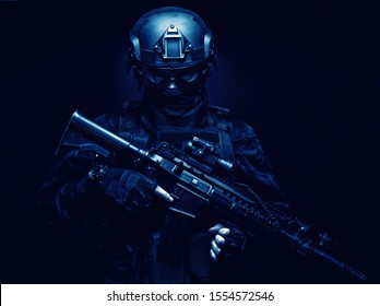 SWAT Fighter, Police Tactical Group Member, Quick Reaction Team Shooter In Black Uniform, Body Armor, Ballistic Goggles And Battle Helmet, Armed Assault Rifle With Optical Sight, Standing In Darkness