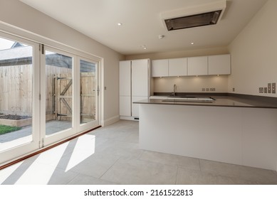 Swavesey, Cambridgeshire, England - May 21 2019: Modern Kitchen In Recently Completed Vacant New Home With Peninsular Island And Bifold Patio Doors