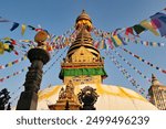 The Swayambhunath Stupa, Temple at golden hour, the golden top is painted with a face and decorated with many colorful prayer flags dancing in the wind, Kathmandu, Nepal 2022