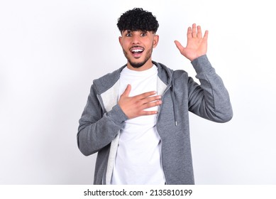 I Swear, Promise You Not Regret. Portrait Of Sincere Young Arab Man With Curly Hair Wearing Casual Clothes Over White Background Raising One Arm And Hold Hand On Heart As Give Oath, Telling Truth,