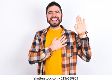 I Swear, Promise You Not Regret. Portrait Of Sincere Young Caucasian Man Wearing Plaid Shirt Over White Background Raising One Arm And Hold Hand On Heart As Give Oath, Telling Truth, 