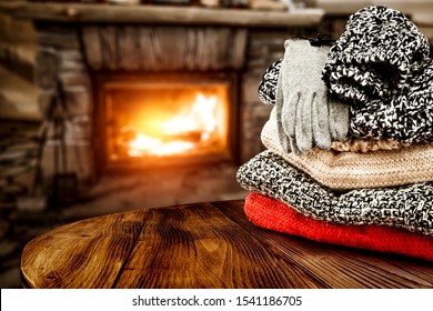 Sweater of winter time and wooden table. Free space for your decoration and fireplace in home interior.