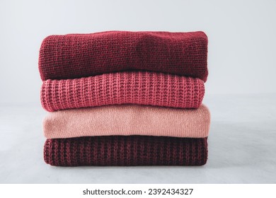 Sweaters. Red, pink sweaters stacked on gray background. - Powered by Shutterstock