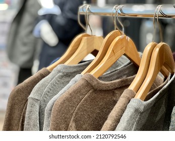sweaters, selective focused closeup row of men's sweaters on hangers in a store.  Collection of warm jumpers hanging on rack in store. textile and clothing concept photo