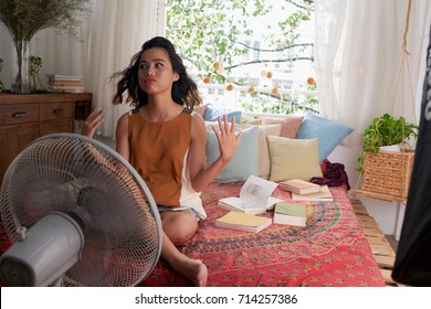 Sweating Asiin girl cooling herself with big fan