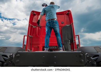 Sweating And Tired Caucasian Trucker In His 30s Staying On The Back Of His Truck Tractor Fifth Wheel Part. Trucking And Transportation Industry Theme.