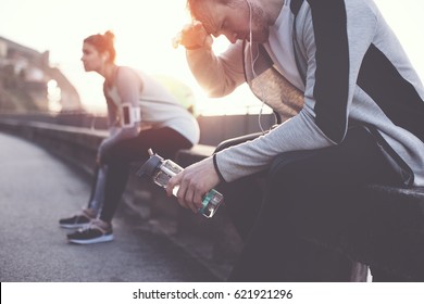 Sweaty Athletes Relaxing On The Bench And Resting After Hard Street Workout Session. Man, Woman And Urban Sport